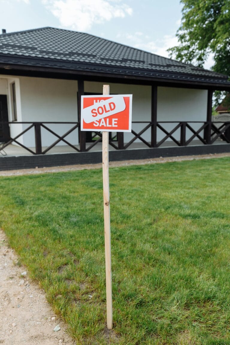 A modern house with a sold sign on a grassy lawn, indicating property purchase.